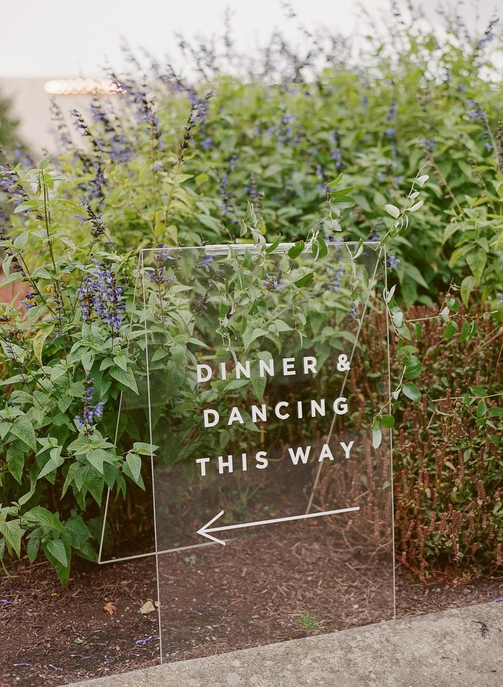 Clear acrylic sign Dinner & Dancing This Way in garden
